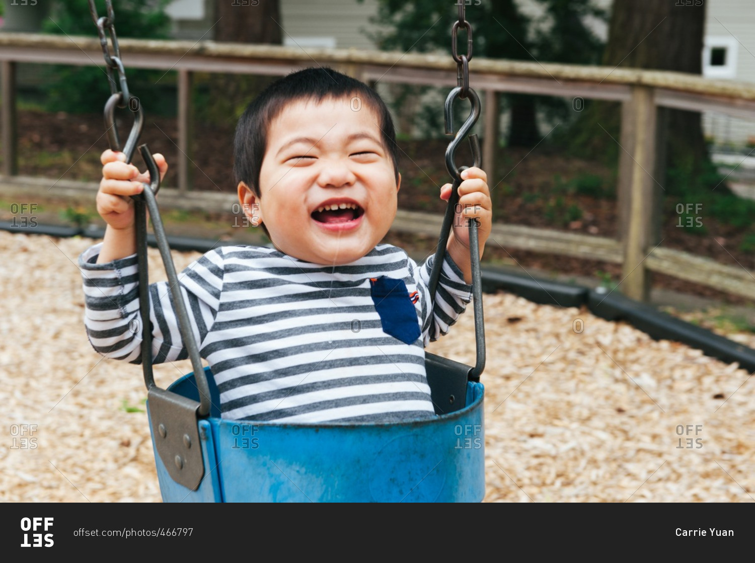 Happy baby boy swinging on a park swing stock photo OFFSET