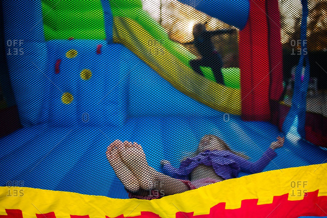 Little girl lying on her back in a colorful bounce house