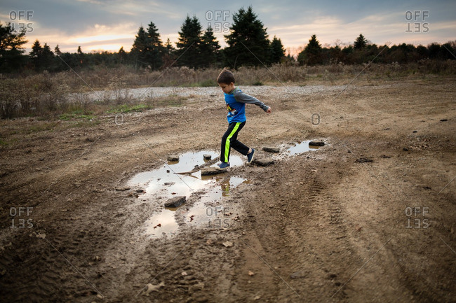 Little boy playing in puddles on a dirt path
