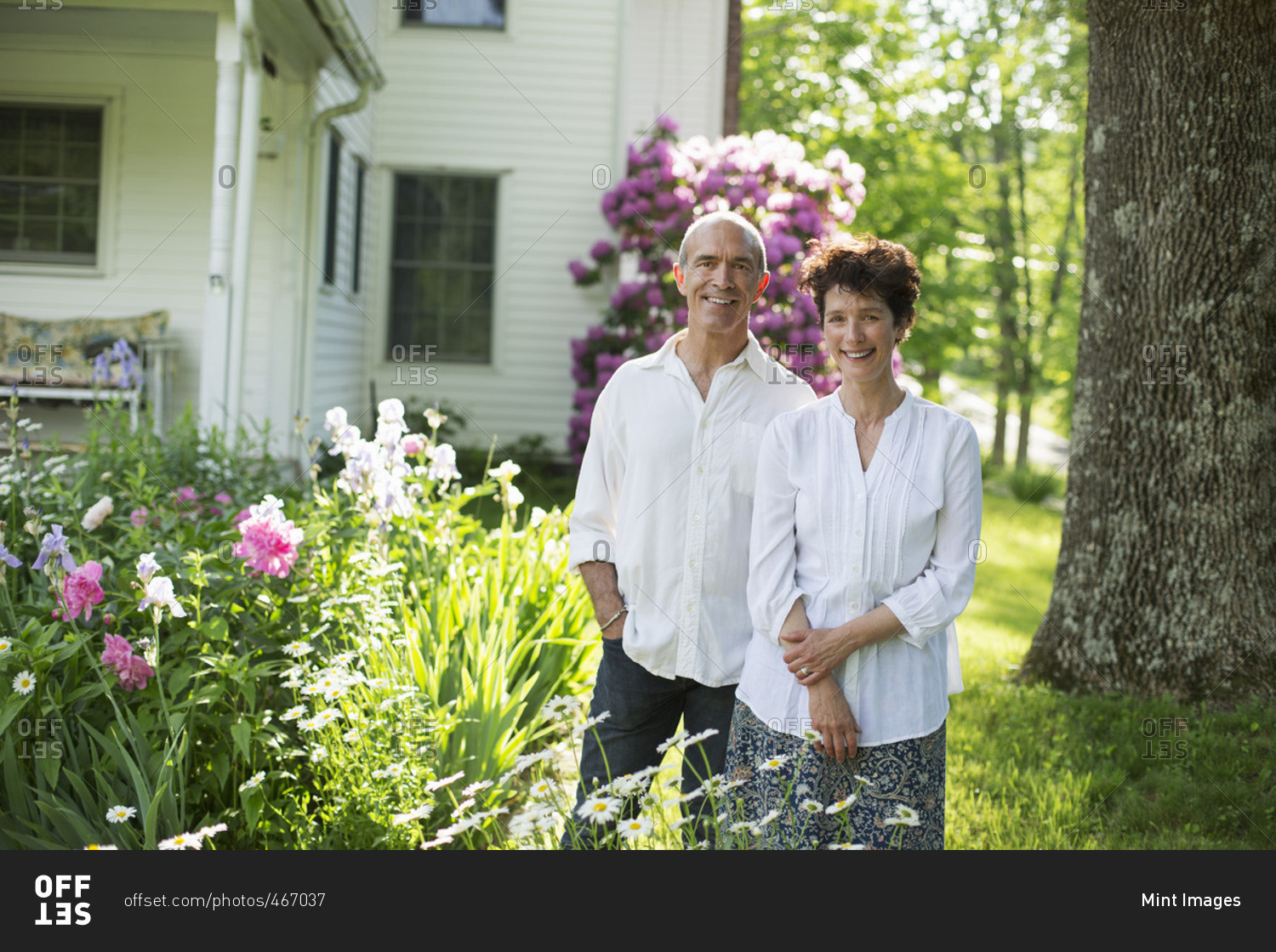 A mature couple in white shirts standing together among flowers