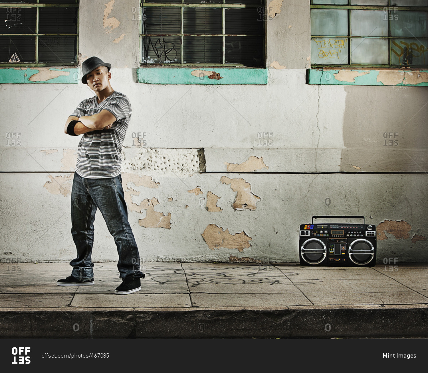 A young man, a breakdance performer with a boombox on the street of a city