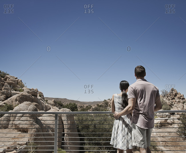 A man and woman on the terrace of an eco house, looking over the rocky landscape