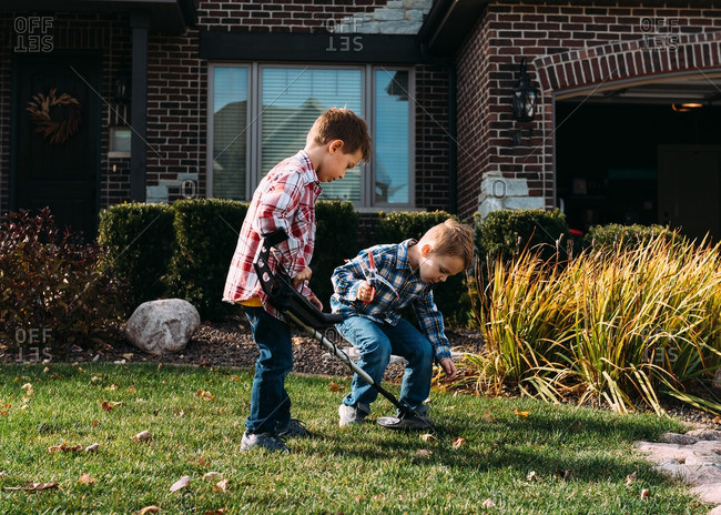 Two boys using a metal detector to search their yard