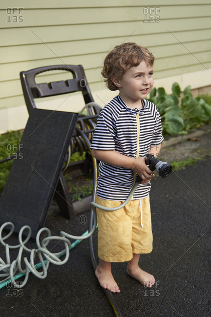 Boy with hose nozzle standing outside