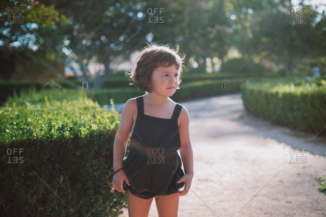 Little girl wearing a black romper walking in a botanical garden