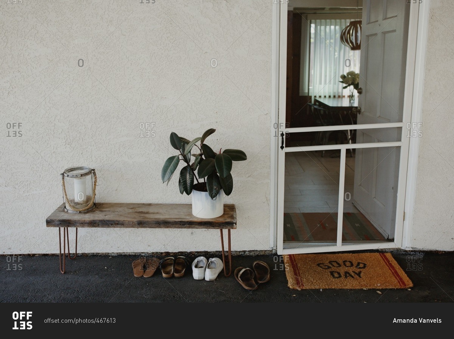 Entrance to home with screen door, welcome mat, and a small table with decorations