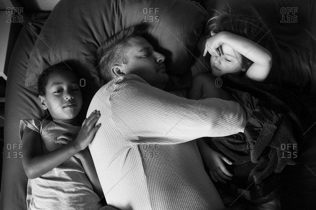 Man taking a nap with his two daughters