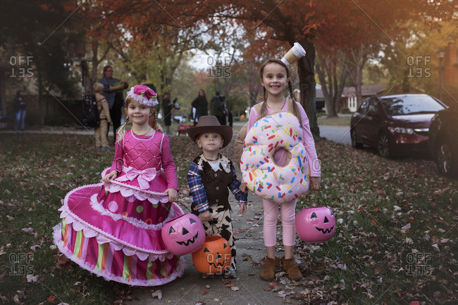 Three Cute Siblings In Halloween Costumes On Sidewalk Stock Photo Offset