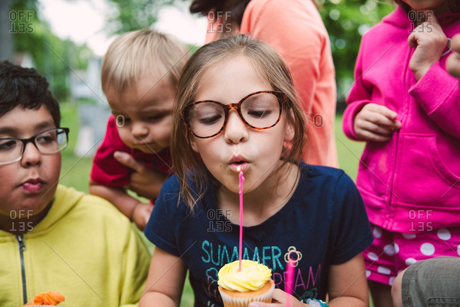 Girl blowing out candle on birthday cupcake