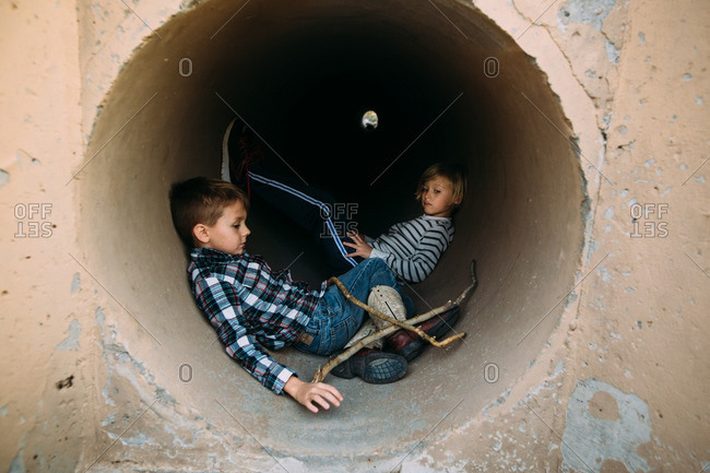 Two kids in concrete tunnel