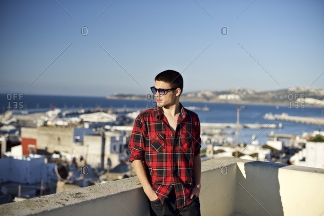 Young man on a rooftop deck overlooking a harbor