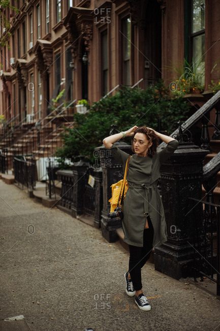 Woman walking on sidewalk in Brooklyn neighborhood, New York