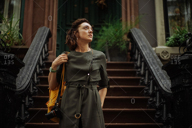 Woman standing in front of steps to historic Brooklyn brownstone home, New York