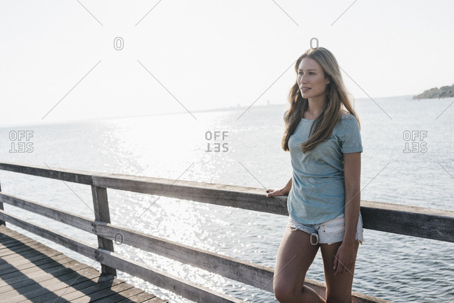 Young woman standing on jetty at backlight