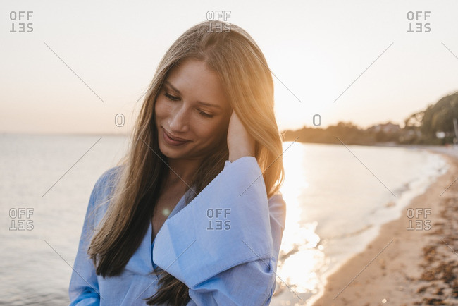 Smiling young woman on the beach at sunset