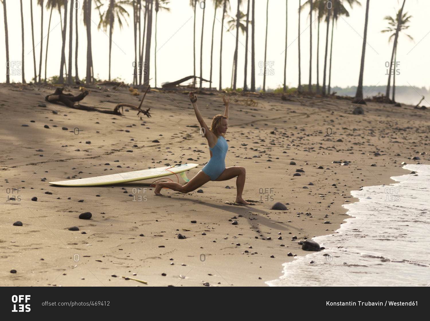 Indonesia- Bali- woman with surfboard stretching on the beach