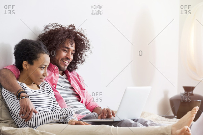 Relaxed couple in bed using laptop