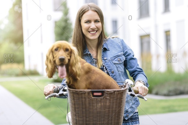 Smiling woman with dog in bicycle basket