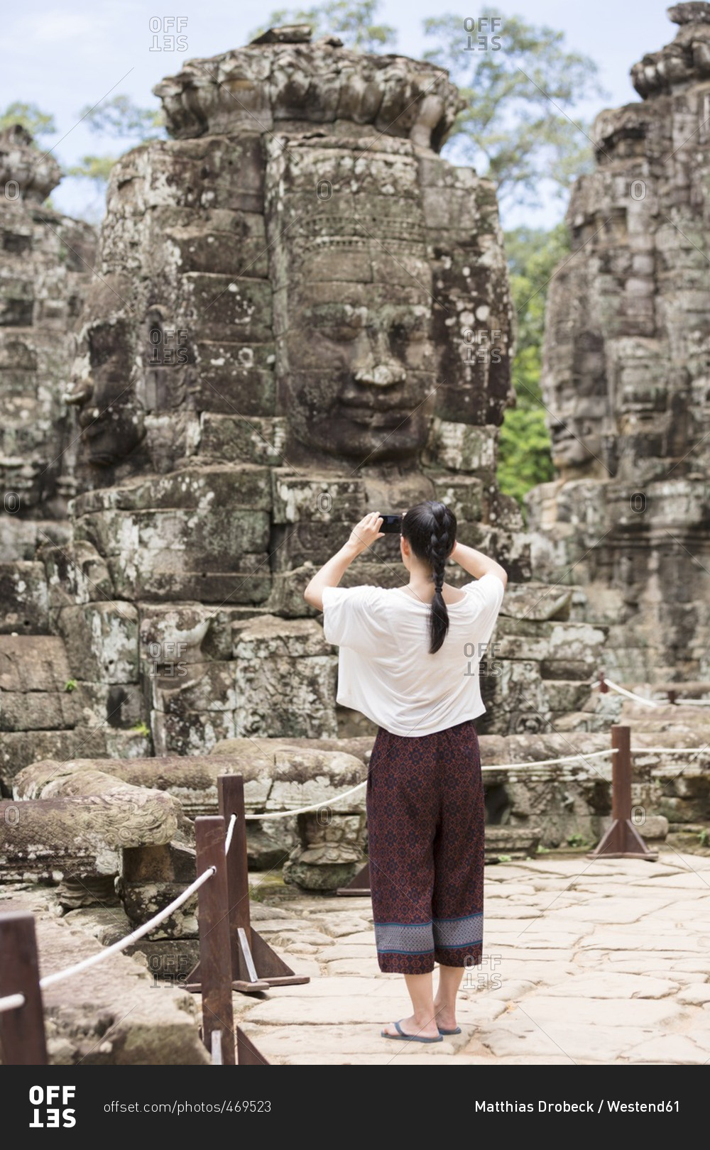 Cambodia- Siem Reap- Angkor Thom- back view of tourist taking pictures of Bayon temple