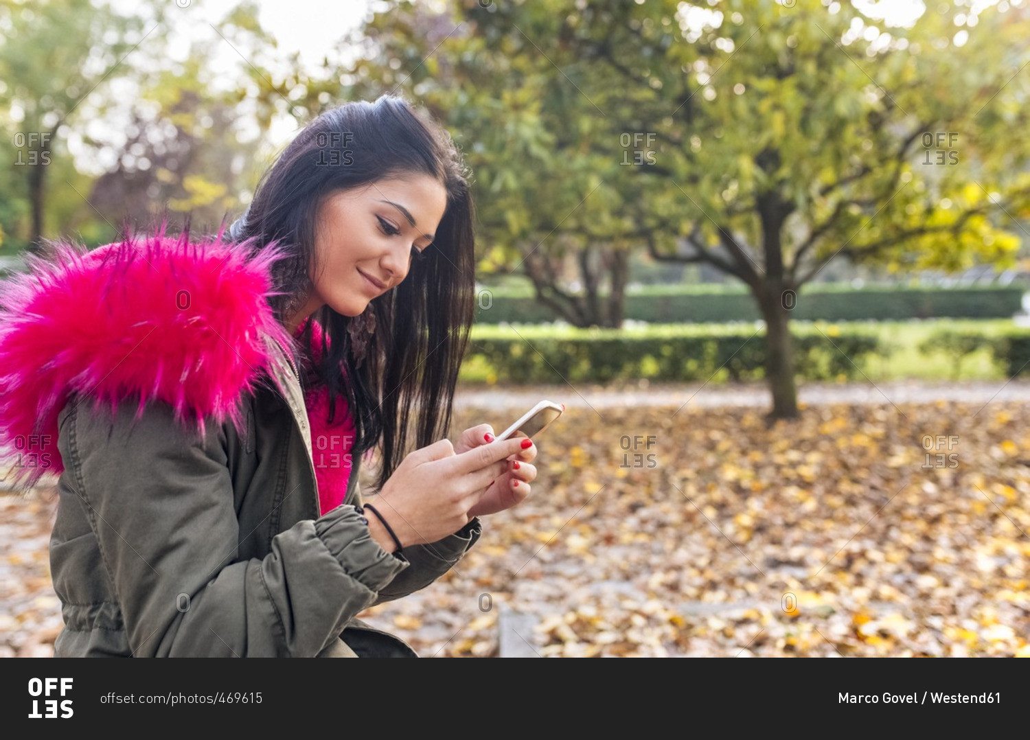 Young woman looking on cell phone in a park in autumn