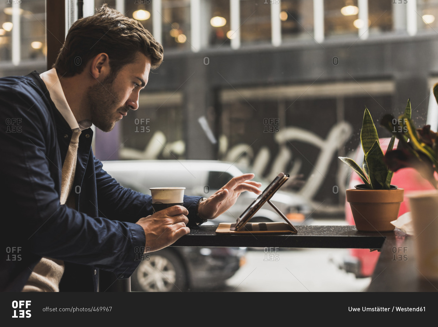 USA- New York City- Businessman sitting in coffee shop- using digital tablet