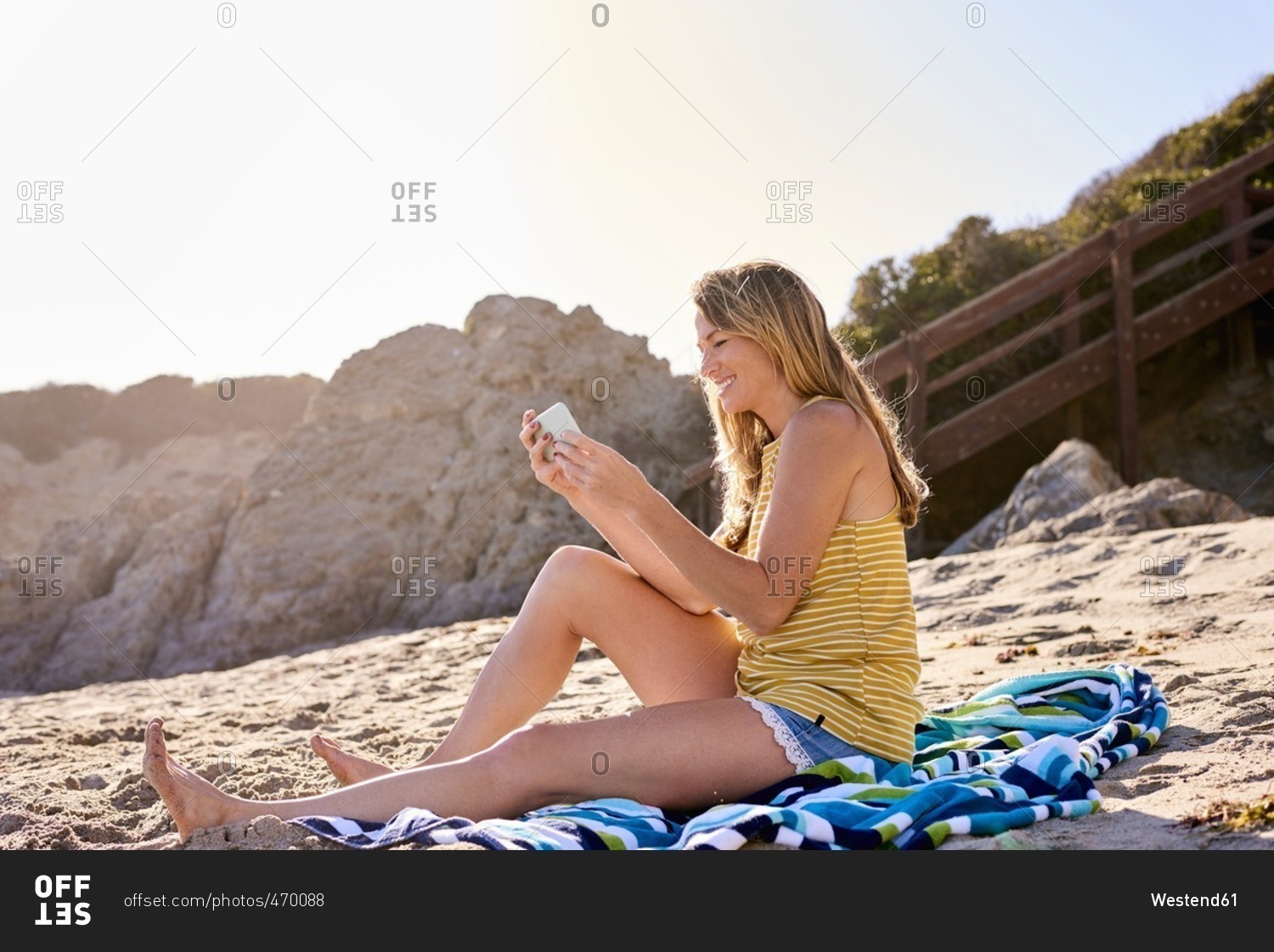 Young woman checking cell phone on the beach