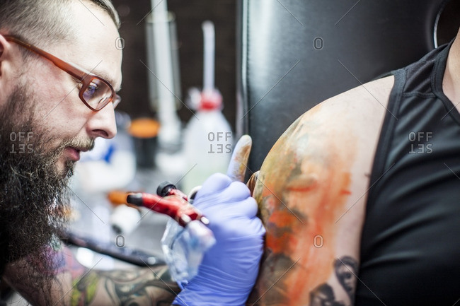 Free Photo | Hands drawing tattoo on arm with needle machine
