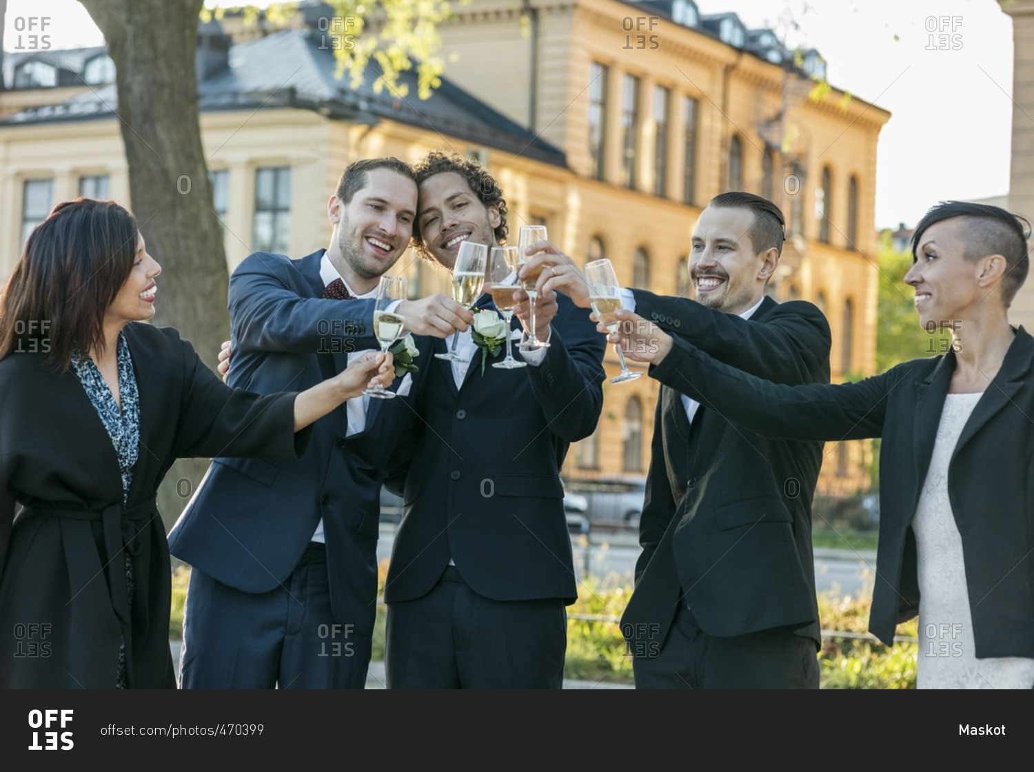 Happy friends raising champagne flutes for toast during wedding ceremony