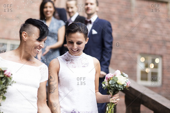 Low Angle View Of Lesbian Couple Against Friends In Background