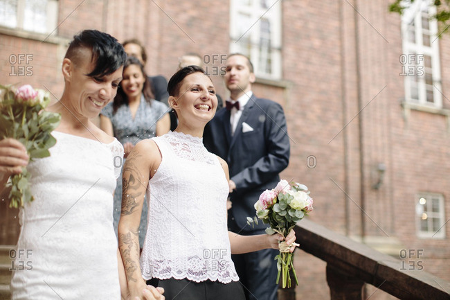 Low Angle View Of Happy Lesbian Couple On Staircase With Guests In