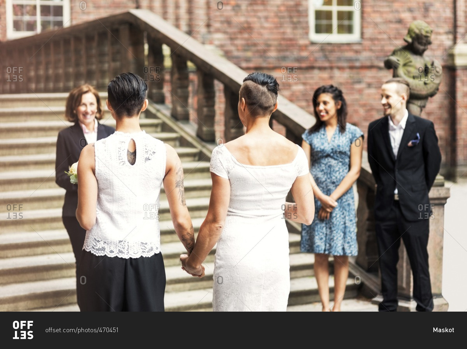 Rear view of lesbian couple standing in front of female priest