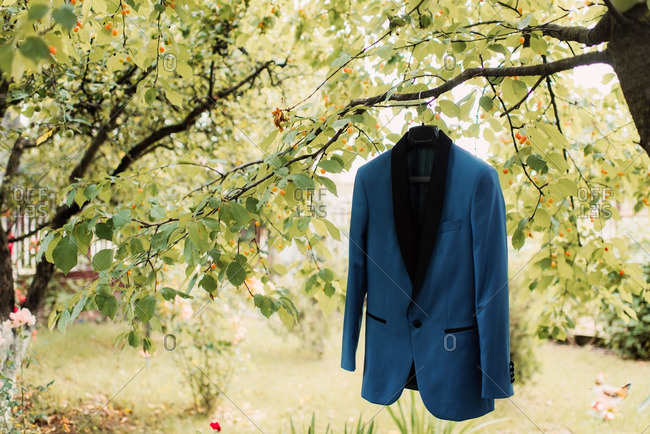 Men's tuxedo jacket hung from a tree branch