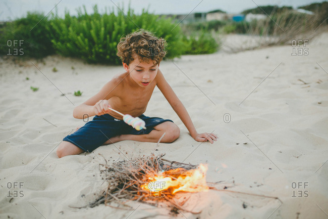 Boy roasting marshmallows on a beach