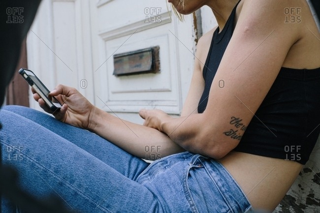 Woman in a black crop top and jeans looking at her phone