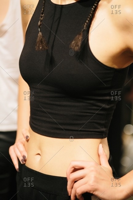 Woman with a black crop top standing with her hands on her hips