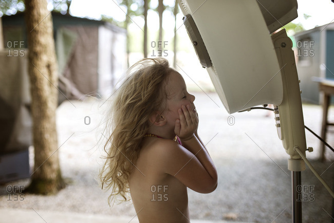Little girl cooling off in front of an electric fan