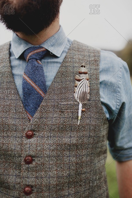 Groom in vest with feather boutonniere