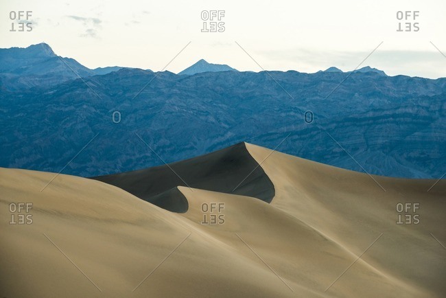 Sand dunes against mountain in Death Valley National Park against sky