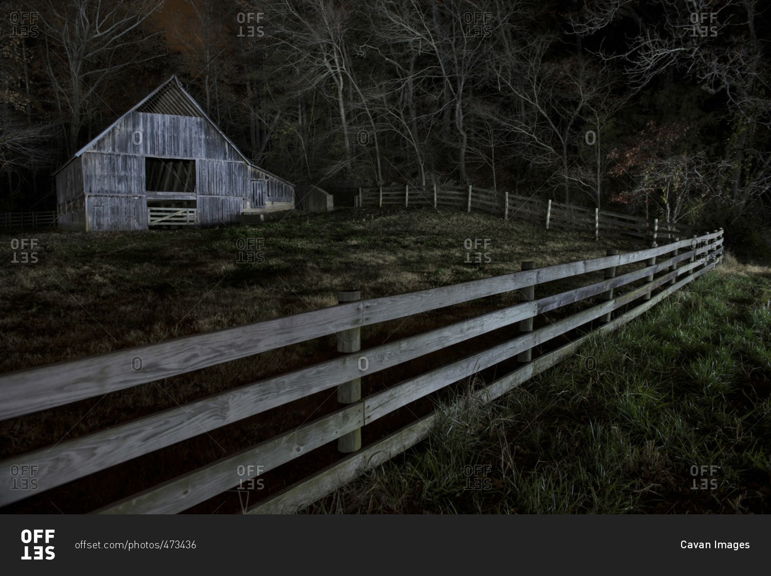 Old barn on field in forest at night stock photo - OFFSET
