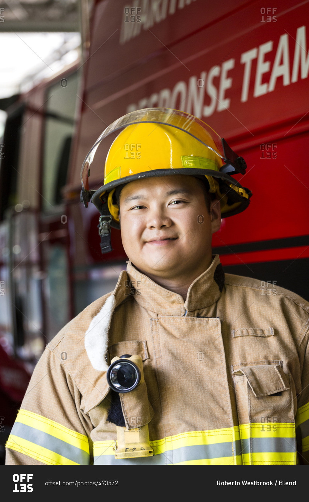 Smiling Chinese fireman standing near fire truck