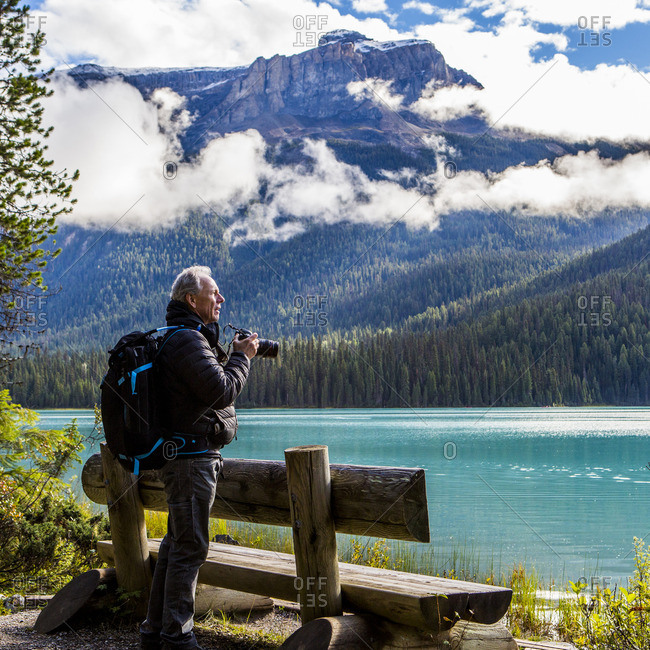 Caucasian man photographing mountain lake