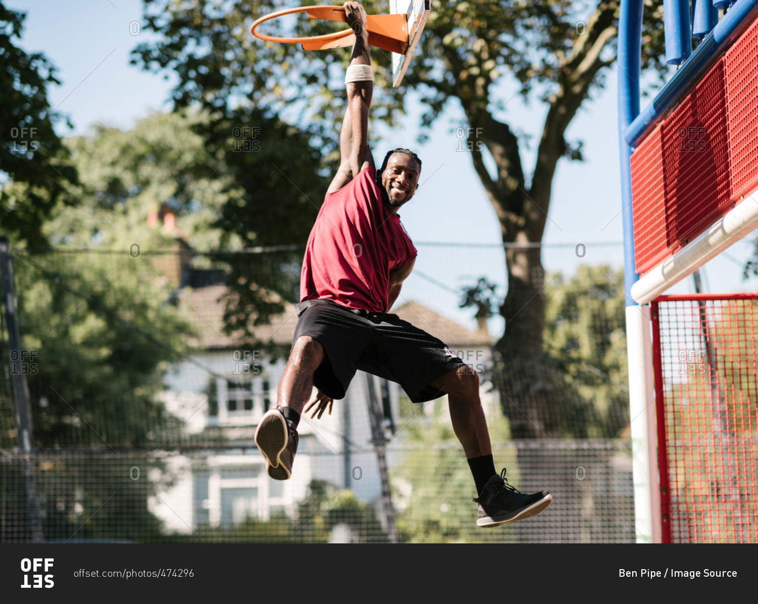 Portrait of young male basketball player hanging from basketball hoop
