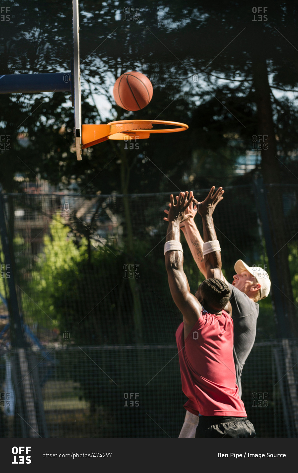 Young male basketball players throwing ball at basketball hoop