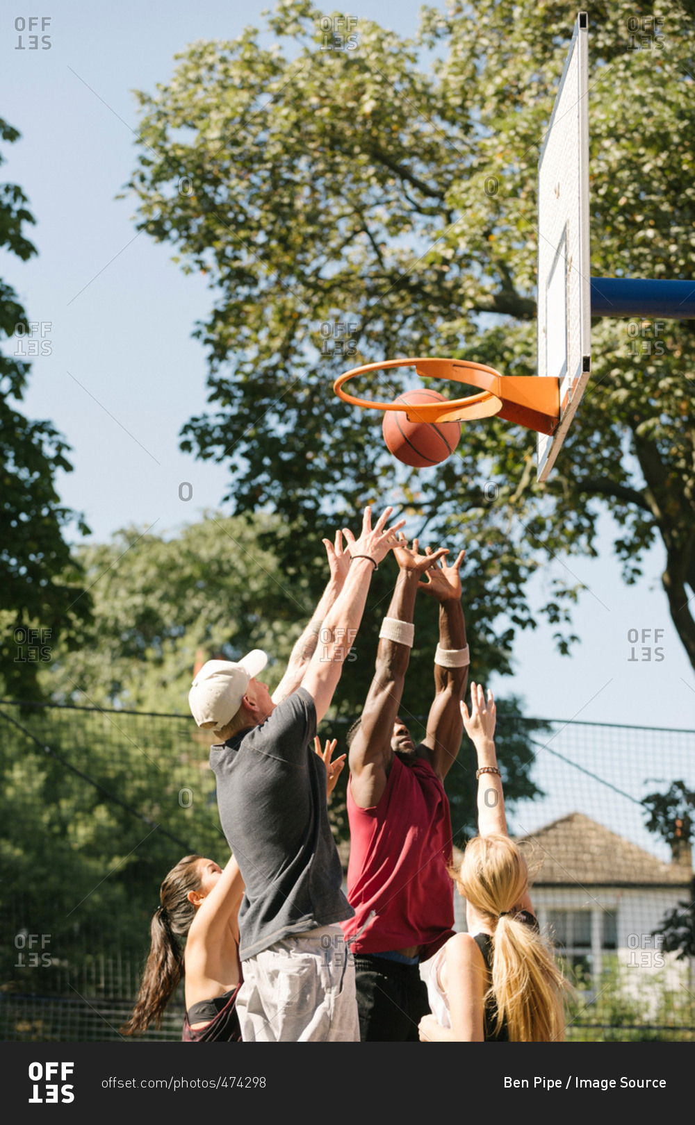 Female and male basketball players throwing ball at basketball hoop
