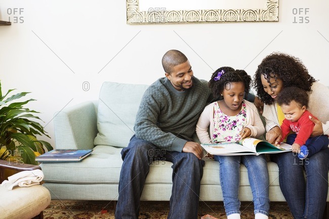 Family looking in picture book while sitting on sofa