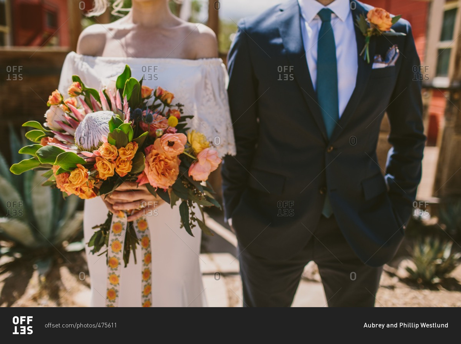 Mid-section of groom and bride holding floral bouquet