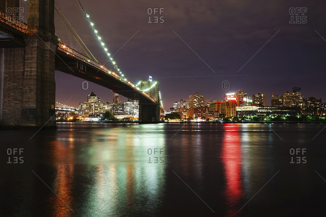 USA, New York, New York City - September 22, 2015: Illuminated Brooklyn Bridge over river against illuminated city