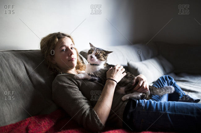 Portrait of woman with cat relaxing on sofa at home