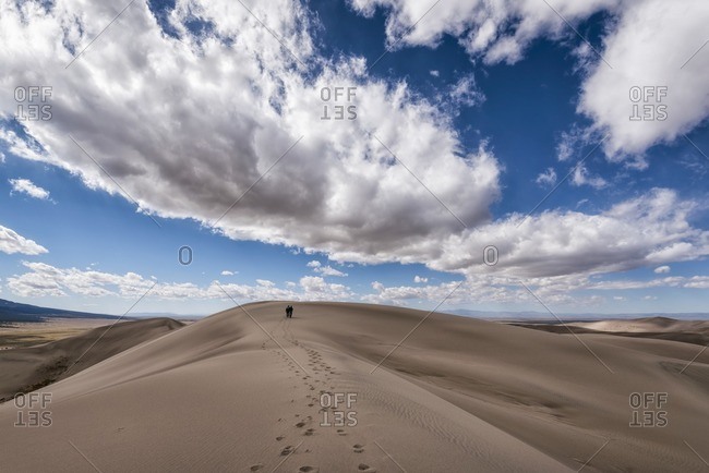 Distant view of people leaving behind footprints in desert
