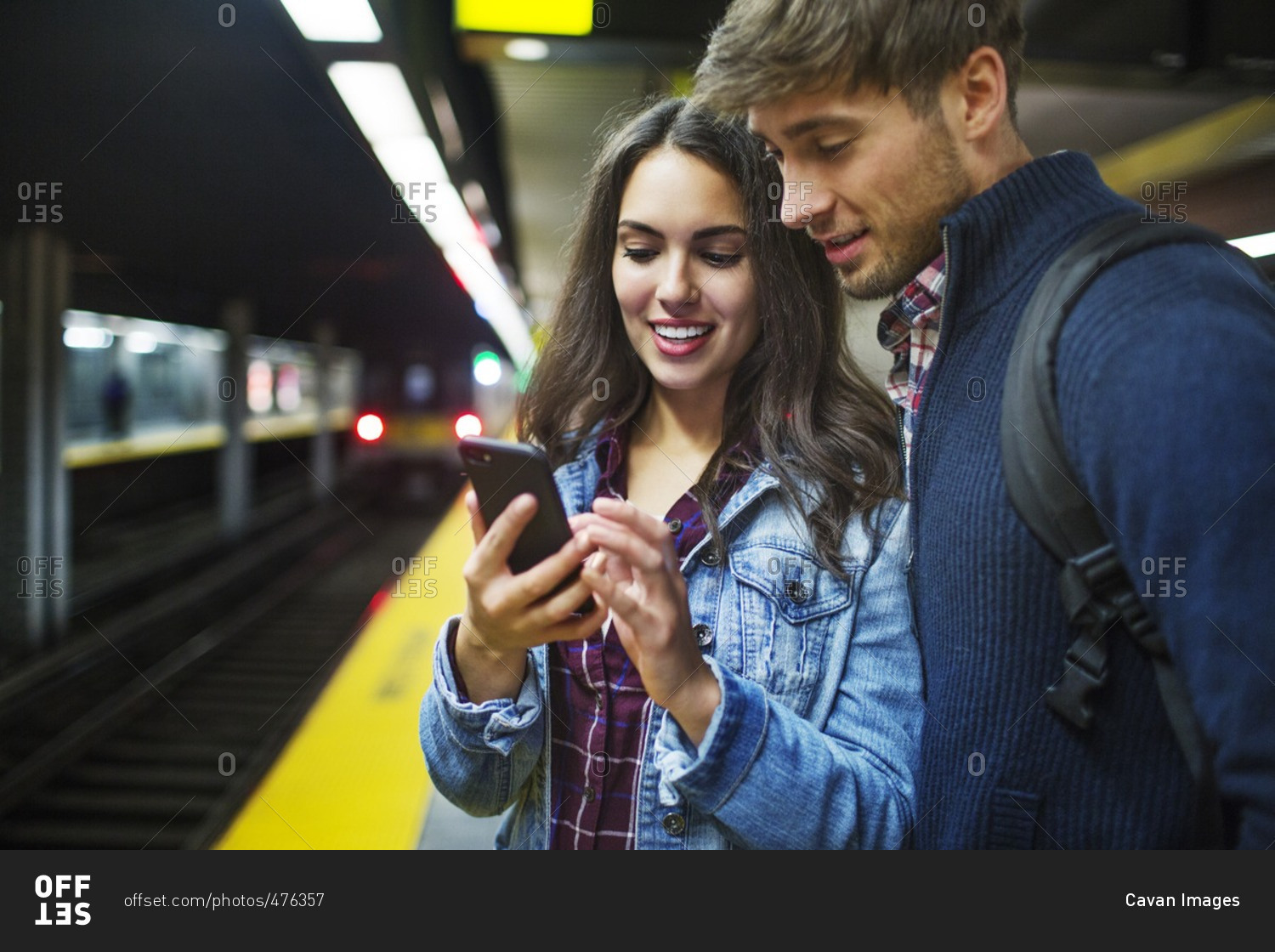 Couple using mobile phone while standing at subway station